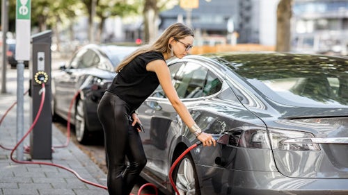 A woman pluging a car to a street charging station 